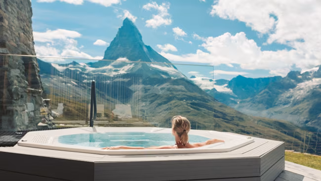 Frau in Whirlpool genießt Bergpanorama beim Wellness, Wellnessurlaub