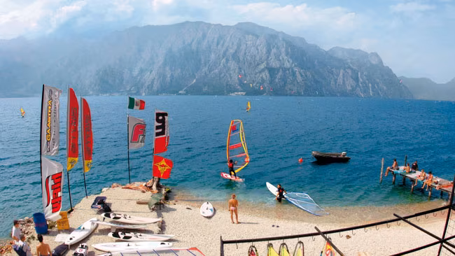 Gardasee - Strandabschnitt im Norden, Treffpunkt für Windsurfer, Berghänge und Gardaseeberge im Hintergrund