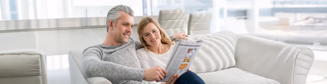 Leserreisen, Paar mit Zeitschrift auf Couch