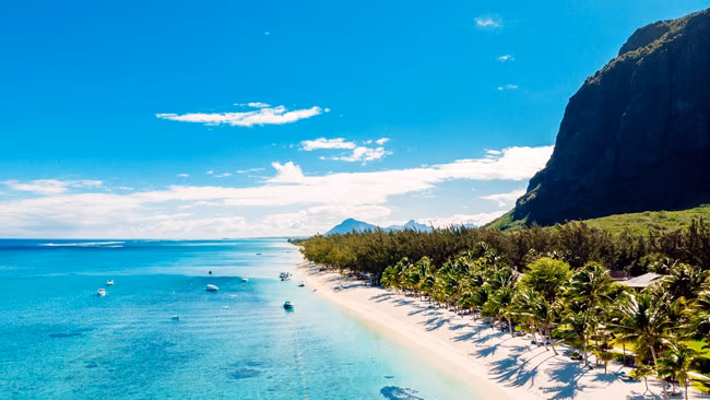 Strand mit Berg in Mauritius mit Palmen und Blaüm Meer, Indischer Ozean
