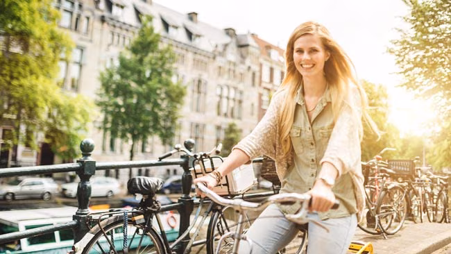 Junge Frau fährt Rad an den Kanälen in Amsterdam, Niederlande