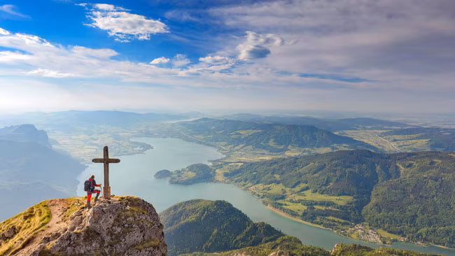 Bergsteiger am Gipfelkreuz am Schafberg mit Blick auf Mondsee, Salzkammergut, Salzburger Land, Österreich