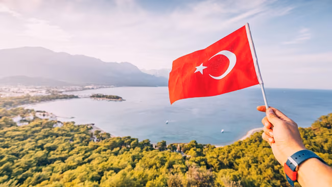 Türkische Flagge in der Hand,Küsteon Kemer und Taurusgebirge, Türkei