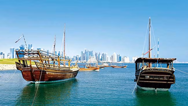 Qatar - Blick auf Skyline von Doha von Meer aus mit Booten im Vordergrund