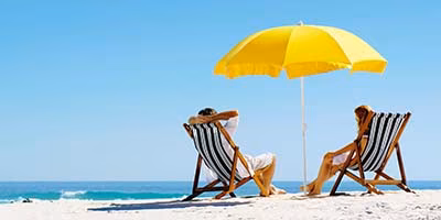 Last Minute Urlaub Strand Paar Sonnenschirm