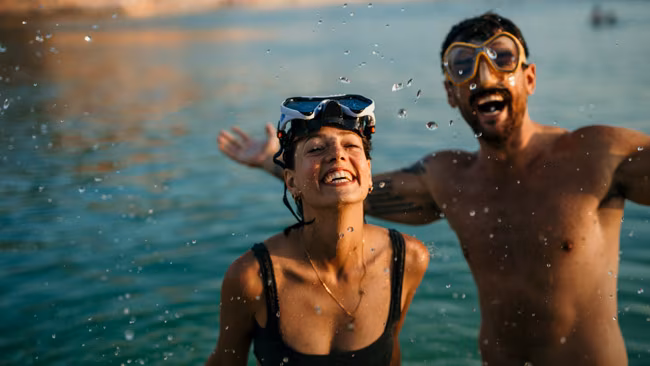 Paar mit Taucherbrillen plantscht im Meer und hat Spaß