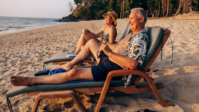 Thailand - Glückliches älteres Paar in Liegestühlen am Strand liegen