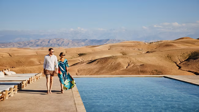 Paar, Hand in Hand laufend an Pool im Wüstencamp, Luxushotel