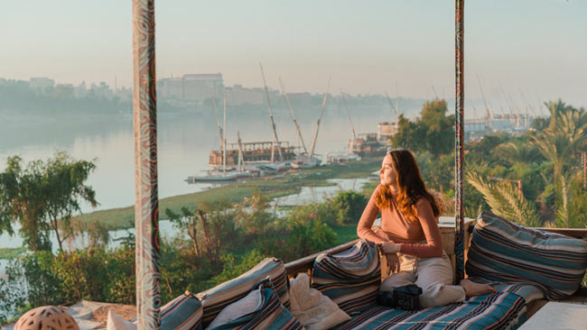 Frau genießt Aussicht auf Nil bei Sonnenuntergang, Nilkreuzfahrtschiffe, Ägypten