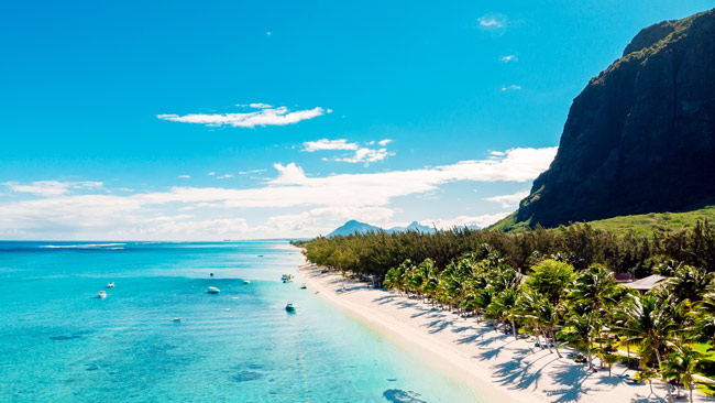 Strand mit Berg in Mauritius mit Palmen und blauem Meer, Indischer Ozean