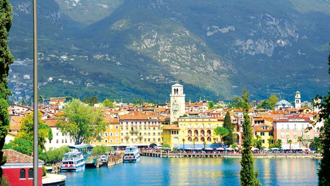 Italien - Gardasee, Uferpromenade Riva del Garda, Berg Torre Apponale im Hintergrund der bunten Häuserfassaden