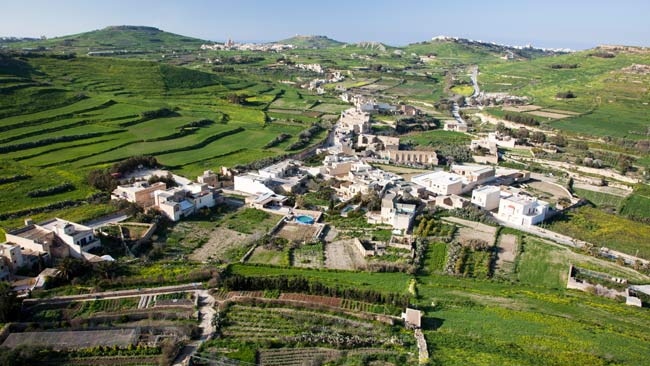 Malta - Insel Gozo, Grüne Felder mit kleinem Dorf mit traditioneller Architektur