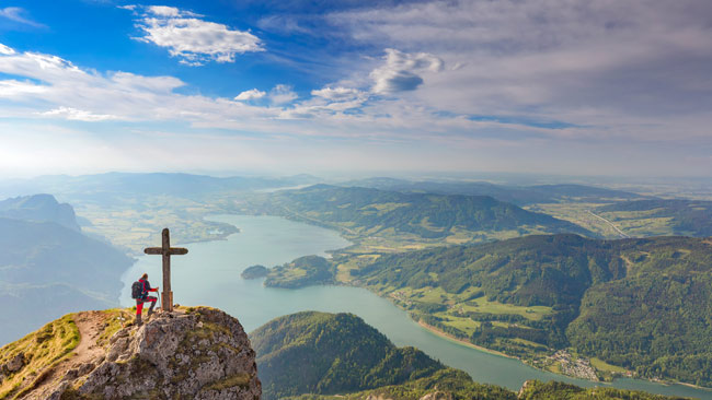 Bergsteiger am Gipfelkreuz am Schafberg mit Blick auf Mondsee, Salzkammergut, Salzburger Land, Österreich