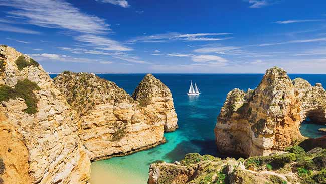 Portugal - Algarve, Bucht mit Felsen und Schiff auf dem Meer