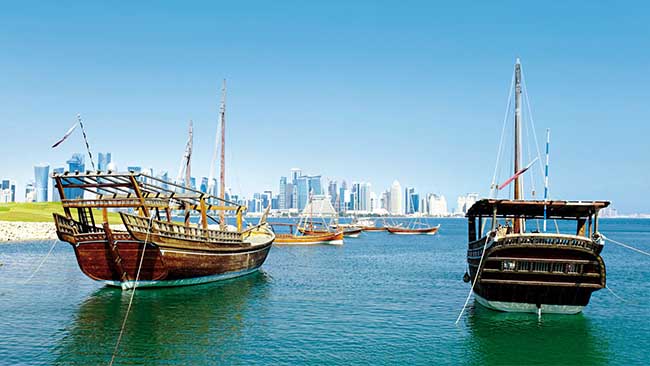 Qatar - Blick auf Skyline von Doha von Meer aus mit Booten im Vordergrund