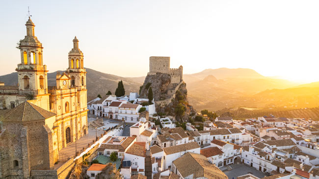 Spanien - Andalusien, Dorf Olvera in Cádiz mit Ansicht auf Kirche Nuestra Señora de der Encarnación auf Hügel im Sonnenuntergang