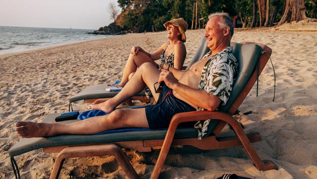Thailand - Glückliches älteres Paar in Liegestühlen am Strand liegen