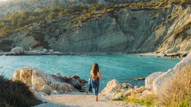 Frau mit Hund laufend an einer Bucht am Meer in der Türkei