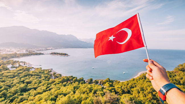 Türkische Flagge in der Hand,Küste von Kemer und Taurusgebirge, Türkei