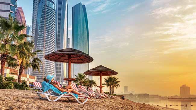Vereinigte Arabische Emirate, Frau am Strand mit Skyline im Hintergrund