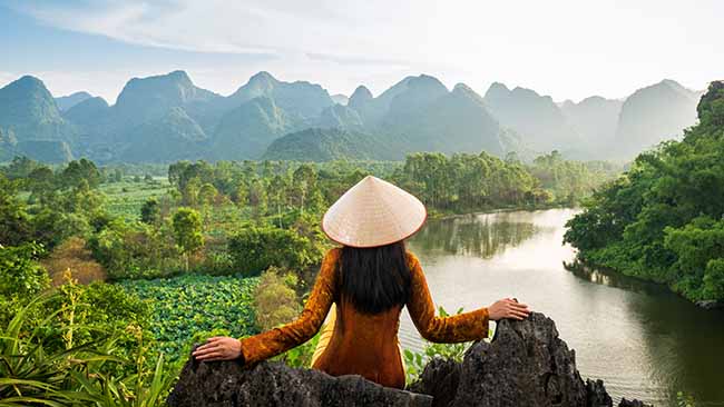Vietnam, Frau am Fluss mit Bergblick