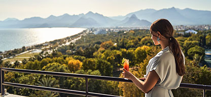 Türkische Riviera - Antalya, Rixos Downtown, Frau steht mit Cocktail auf dem Balkon und blickt auf das Meer