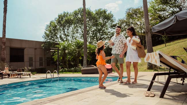 Familie mit Kind bei Anreise am Hotelpool, Badespaß