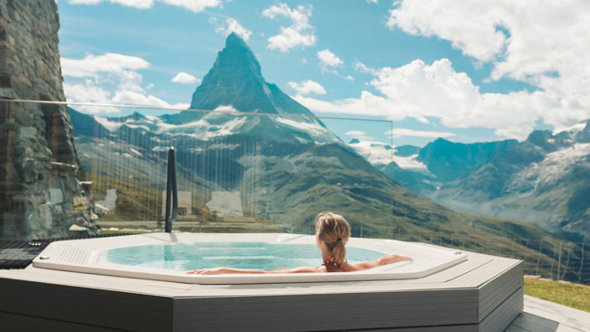 Frau in Whirlpool genießt Bergpanorama beim Wellness, Wellnessurlaub