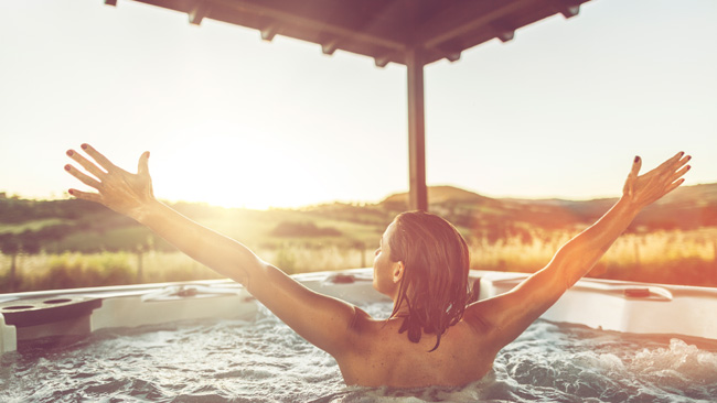 Frau mit offenen Armen in Whirlpool im Wellnesurlaub, Wellness