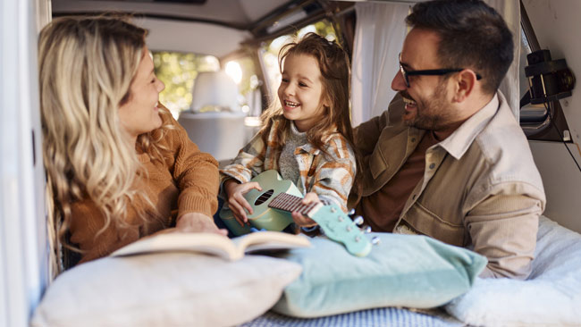 Junge glückliche Familie, die sich in einem Wohnmobilanhänger entspannt, Campingurlaub