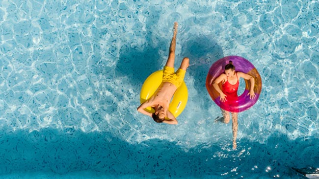 Paar entspannt in Schwimmreifen im Pool im Sommerurlaub