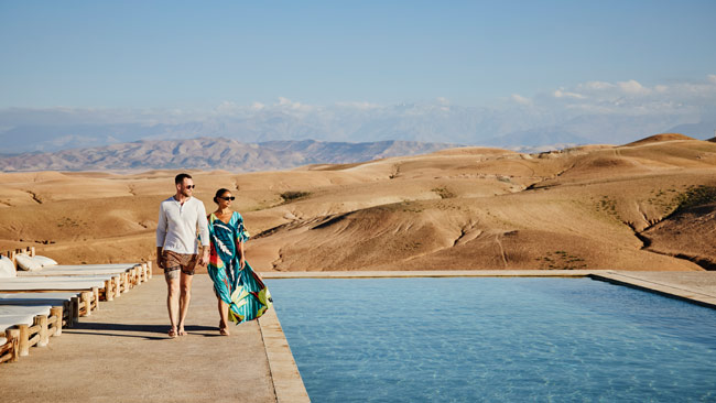 Paar, Hand in Hand laufend an Pool im Wüstencamp, Luxushotel