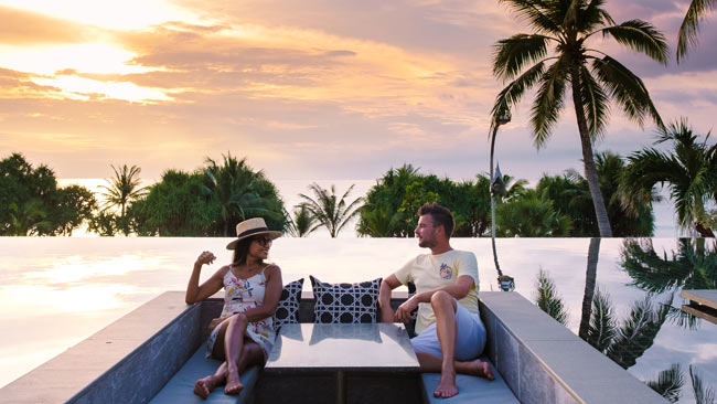 Thailand - Paar genießt Sonnenuntergang in Lounge am Strand, Luxusurlaub
