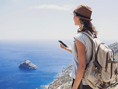 Frau mit Handy in der Hand am Meer