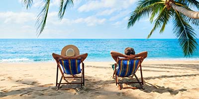 Strandurlaub, Paar im Liegestuhl mit Palmen